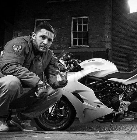 Tom posing with his white Ducati Supersport S. What's his net worth, salary, and other assets valuation